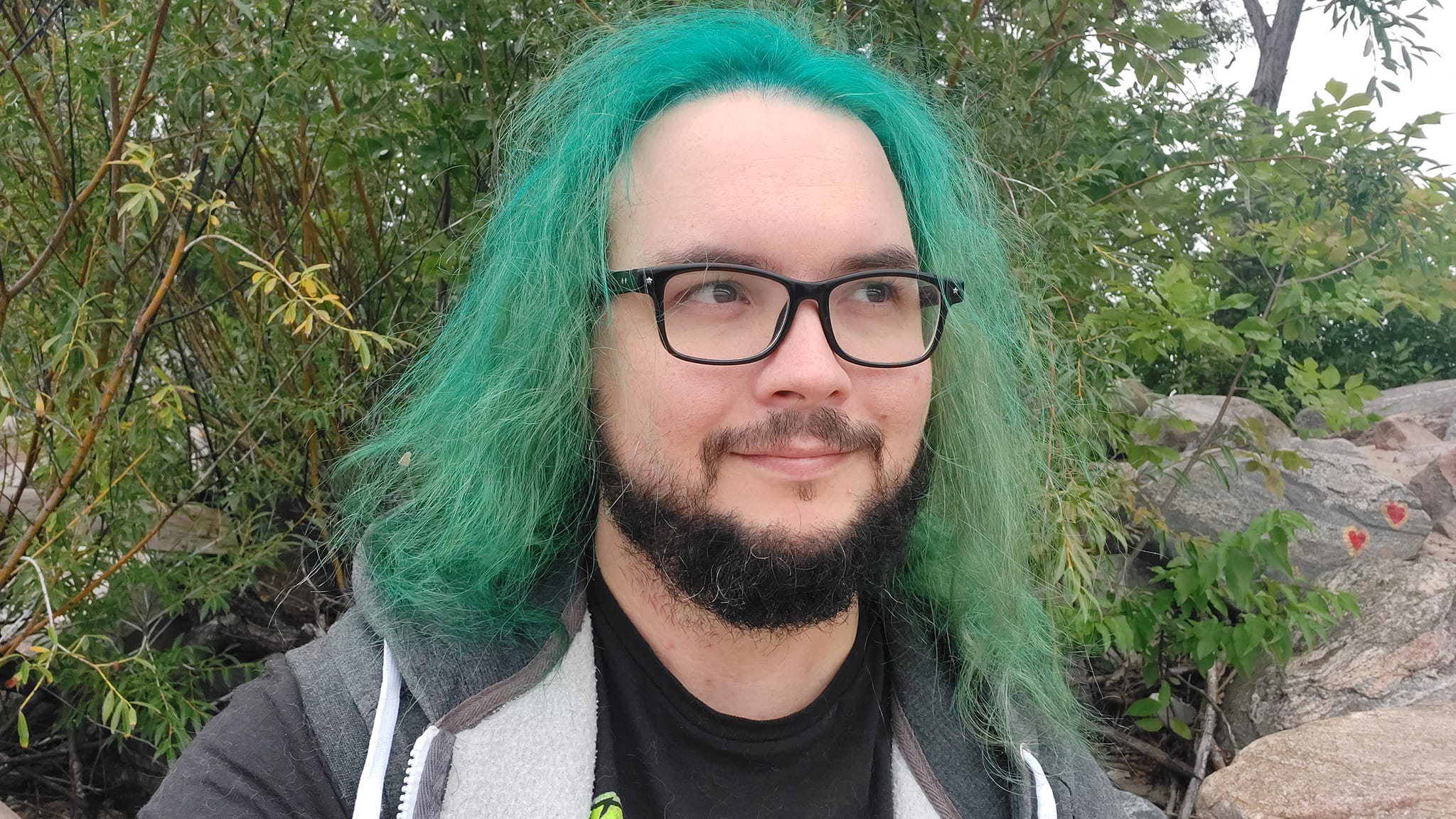 A man with green hair stands outside at a boulder breakwater, photo 7